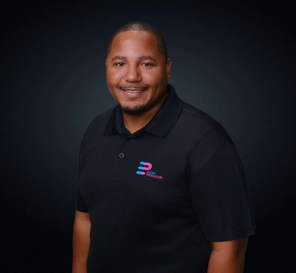 Bobby Dent - Live Event Production | Management | Event Producers - Live Event Production | Management | Event Producers Portrait of a smiling man in a black polo shirt featuring a colorful Event Producers logo on the chest.