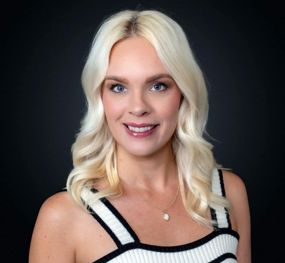 Kristy Quick - Live Event Production | Management | Event Producers - Live Event Production | Management | Event Producers Portrait of a smiling blonde woman in a black-and-white striped top against a dark background, head and shoulders.